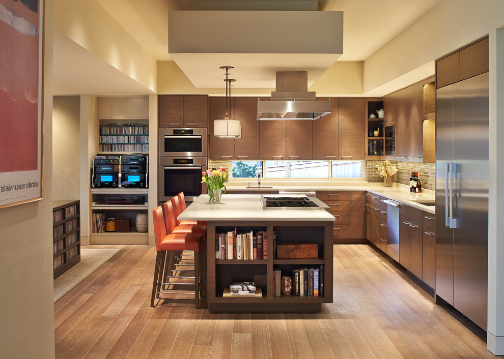 Inspiration for a large contemporary l-shaped open plan kitchen in Seattle with a submerged sink, flat-panel cabinets, dark wood cabinets, engineered stone countertops, brown splashback, glass tiled splashback, stainless steel appliances, medium hardwood flooring and an island.