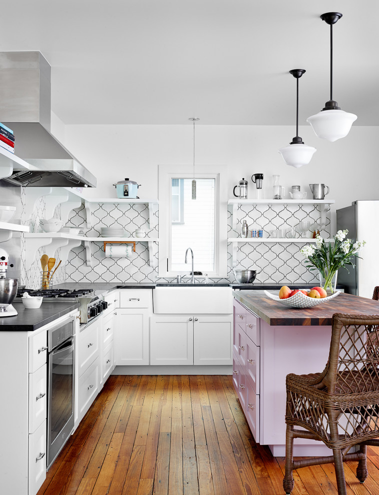 Eat-in kitchen - coastal l-shaped medium tone wood floor eat-in kitchen idea in Austin with a farmhouse sink, shaker cabinets, white cabinets, soapstone countertops, white backsplash, ceramic backsplash, stainless steel appliances and an island