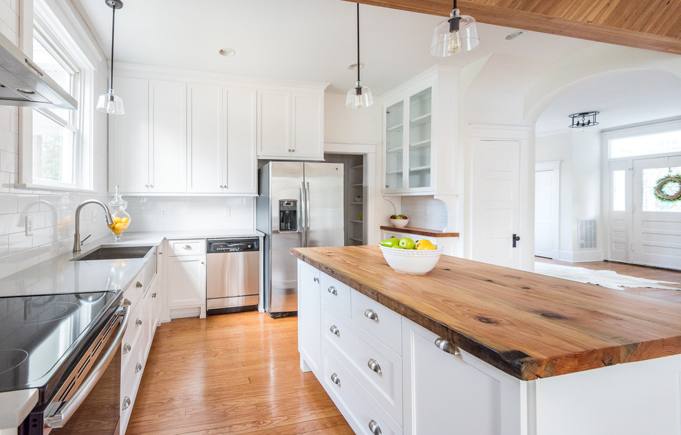 Eat-in kitchen - large farmhouse l-shaped medium tone wood floor eat-in kitchen idea in Richmond with a farmhouse sink, shaker cabinets, white cabinets, wood countertops, white backsplash, subway tile backsplash, stainless steel appliances and an island