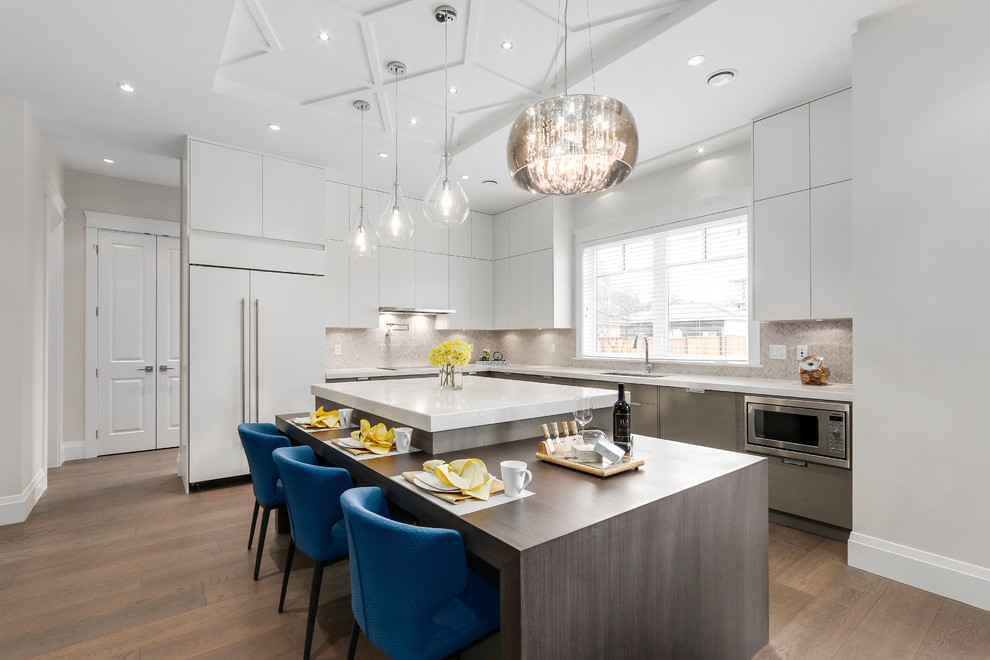 Contemporary l-shaped kitchen in Vancouver with flat-panel cabinets, white cabinets, grey splashback, mosaic tiled splashback, integrated appliances, dark hardwood flooring, an island and brown floors.