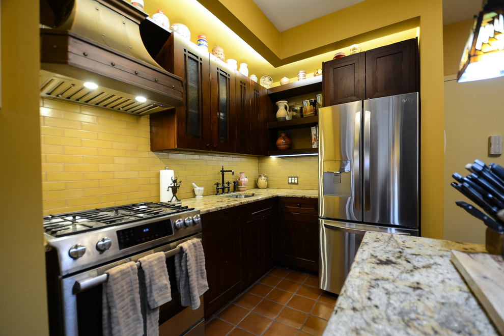Inredning av ett amerikanskt mellanstort flerfärgad linjärt flerfärgat kök med öppen planlösning, med en undermonterad diskho, luckor med infälld panel, skåp i mörkt trä, bänkskiva i kvartsit, gult stänkskydd, stänkskydd i tunnelbanekakel, rostfria vitvaror, klinkergolv i terrakotta, en köksö och orange golv
