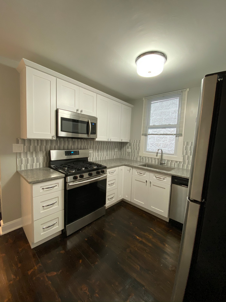 Modern inredning av ett litet grå grått kök, med en undermonterad diskho, skåp i shakerstil, vita skåp, grått stänkskydd, stänkskydd i stickkakel och rostfria vitvaror