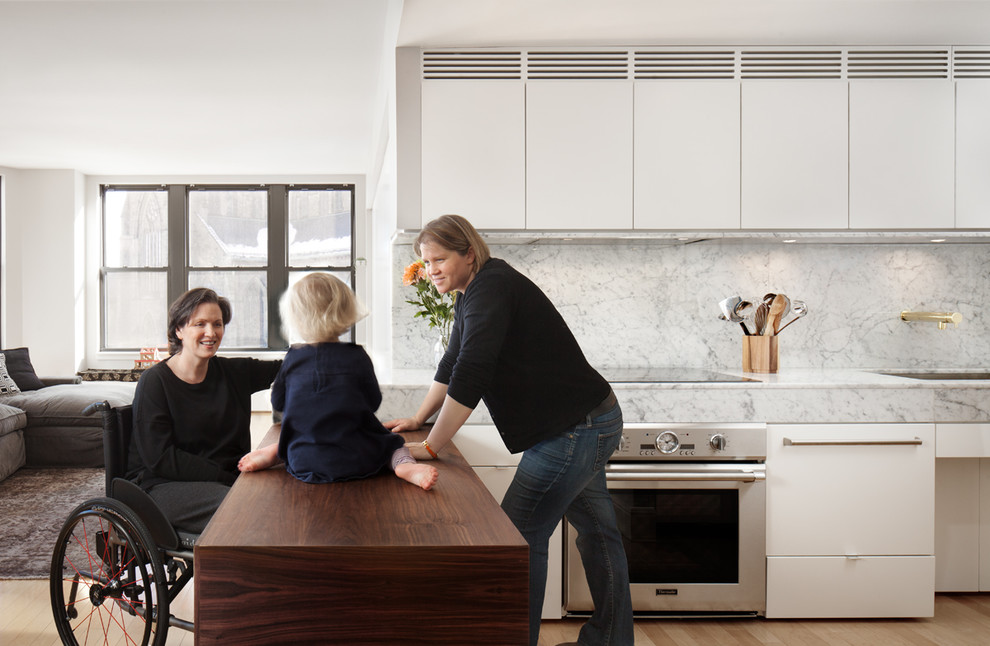 Foto di una cucina moderna di medie dimensioni con lavello sottopiano, ante lisce, ante bianche, top in marmo, elettrodomestici da incasso, parquet chiaro e penisola