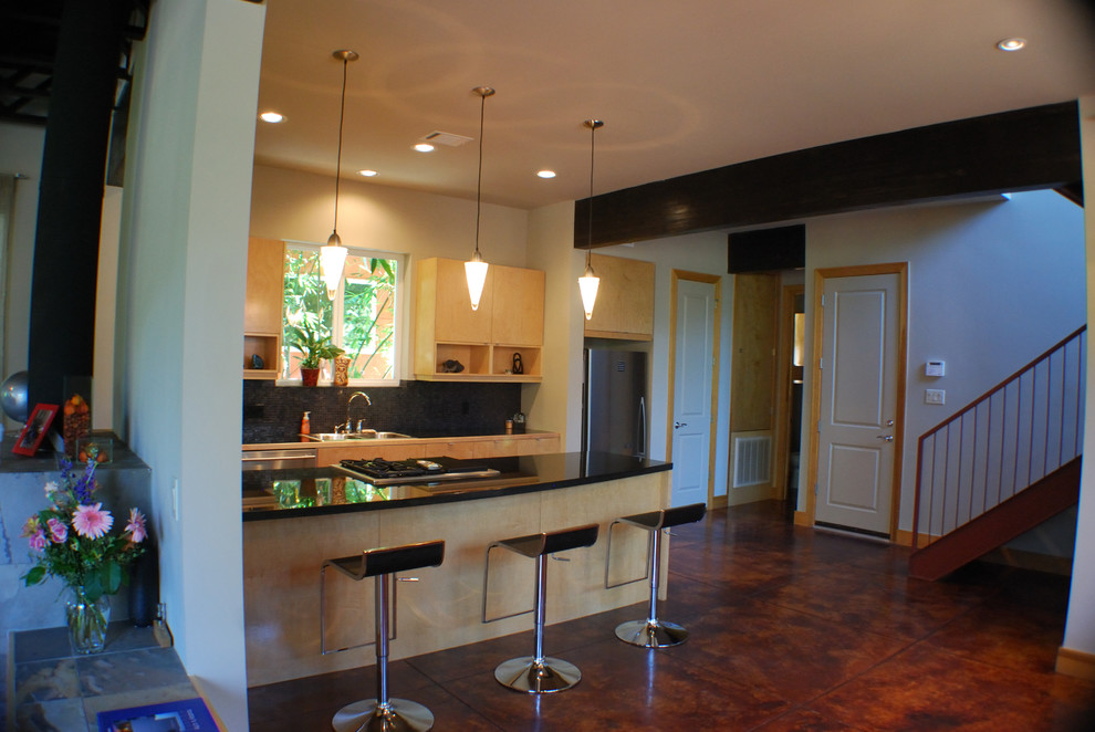 Foto di una cucina contemporanea con ante lisce, ante in legno chiaro, top in granito, elettrodomestici in acciaio inossidabile e pavimento in cemento