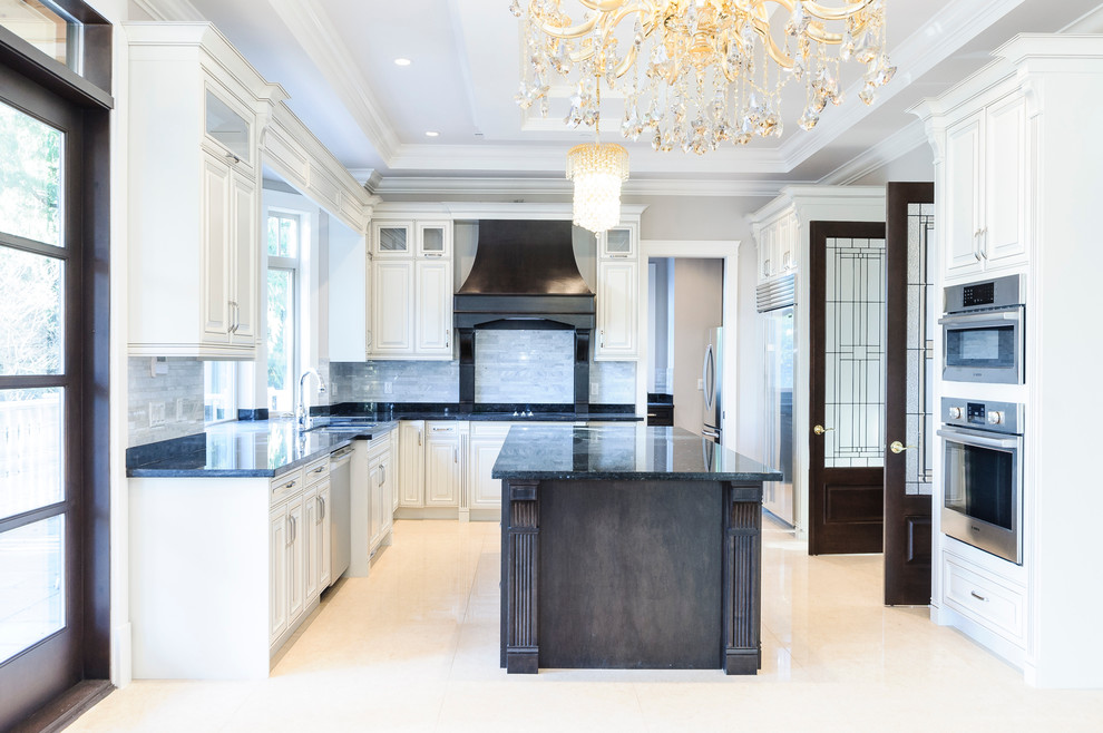 This is an example of a medium sized classic u-shaped kitchen/diner in Vancouver with a submerged sink, raised-panel cabinets, granite worktops, grey splashback, stone tiled splashback, stainless steel appliances, travertine flooring, an island, white cabinets and beige floors.