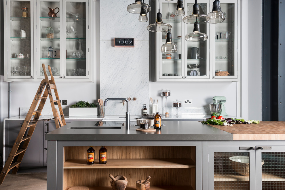 ロンドンにある高級な中くらいなインダストリアルスタイルのおしゃれなアイランドキッチン (グレーのキャビネット、グレーのキッチンパネル、石スラブのキッチンパネル) の写真