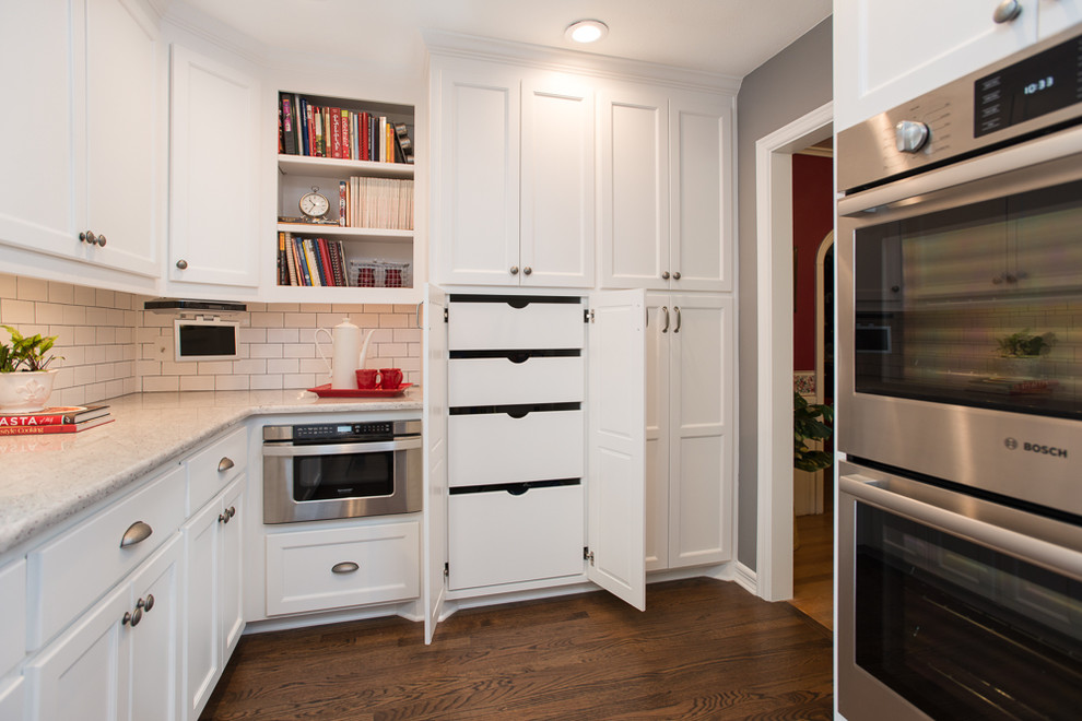 Inspiration for a medium sized classic galley enclosed kitchen in Dallas with recessed-panel cabinets, white cabinets, white splashback, ceramic splashback, stainless steel appliances, medium hardwood flooring, no island, brown floors, a submerged sink and granite worktops.