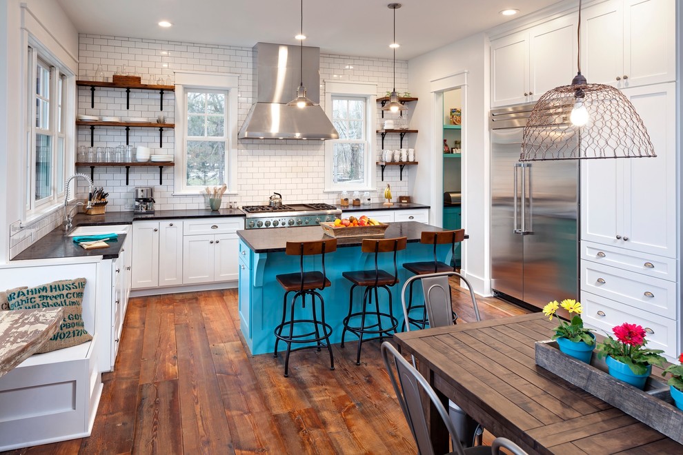 Eat-in kitchen - eclectic l-shaped medium tone wood floor eat-in kitchen idea in Chicago with a farmhouse sink, flat-panel cabinets, white cabinets, granite countertops, white backsplash, subway tile backsplash, stainless steel appliances and an island