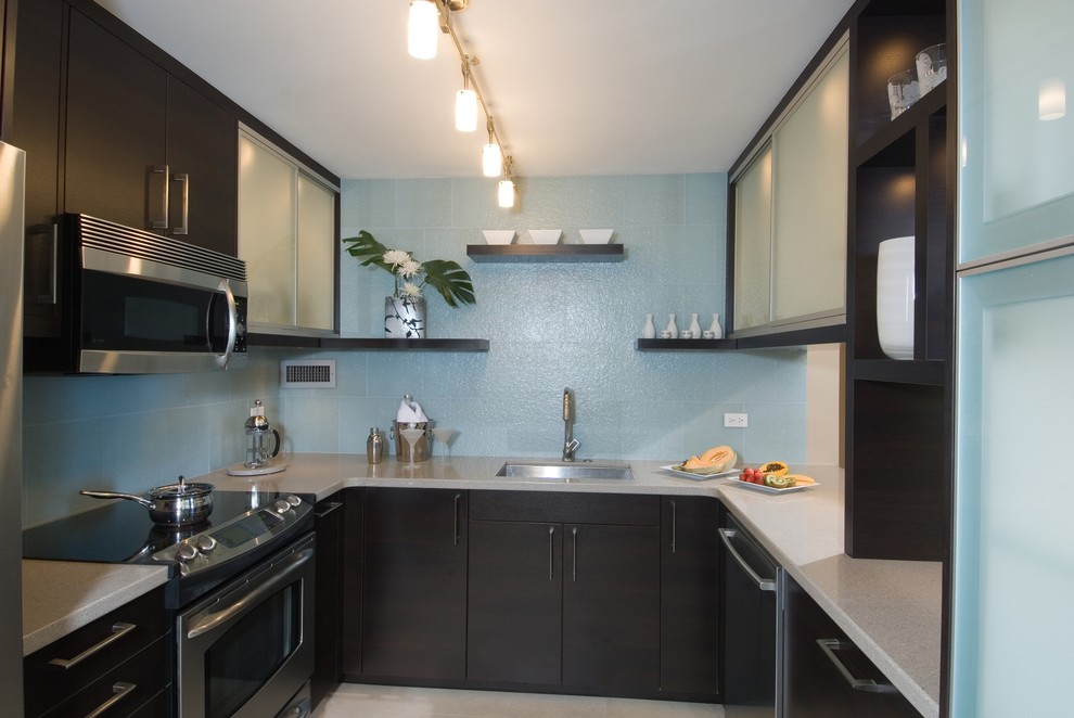 Bild på ett funkis kök och matrum, med en undermonterad diskho, släta luckor, skåp i mörkt trä, bänkskiva i koppar, blått stänkskydd, stänkskydd i glaskakel och rostfria vitvaror
