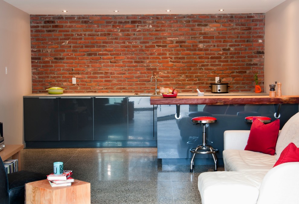 バンクーバーにある高級な広いコンテンポラリースタイルのおしゃれなキッチン (コンクリートの床、フラットパネル扉のキャビネット、グレーのキャビネット、コンクリートカウンター、赤いキッチンパネル、ドロップインシンク) の写真
