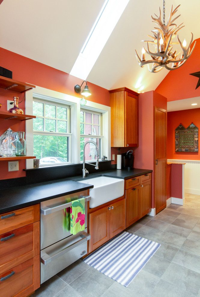 Example of a mid-sized mountain style galley slate floor, gray floor and vaulted ceiling enclosed kitchen design in Burlington with a farmhouse sink, recessed-panel cabinets, medium tone wood cabinets, granite countertops, black backsplash, granite backsplash, stainless steel appliances, no island and black countertops
