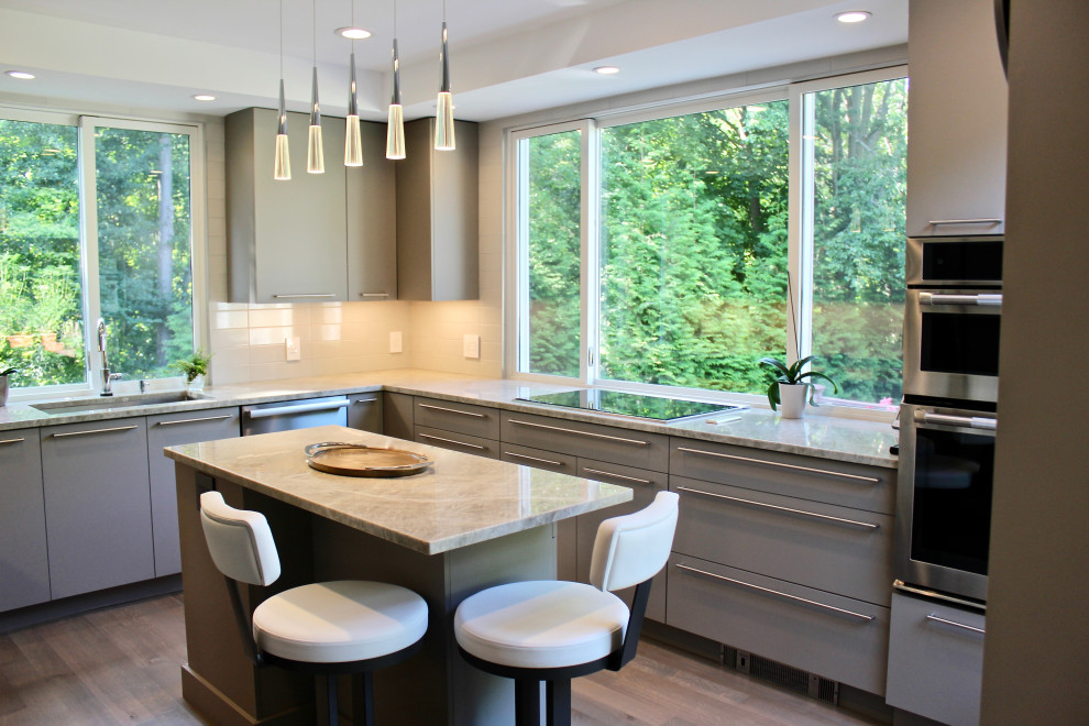 This is an example of a medium sized contemporary u-shaped kitchen/diner in Boston with a submerged sink, flat-panel cabinets, grey cabinets, quartz worktops, beige splashback, porcelain splashback, stainless steel appliances, light hardwood flooring, an island, grey floors and grey worktops.