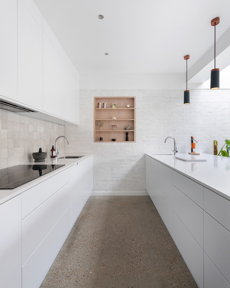 Réalisation d'une cuisine parallèle design avec un évier encastré, un placard à porte plane, des portes de placard blanches, sol en béton ciré, une péninsule, un sol gris et un plan de travail blanc.