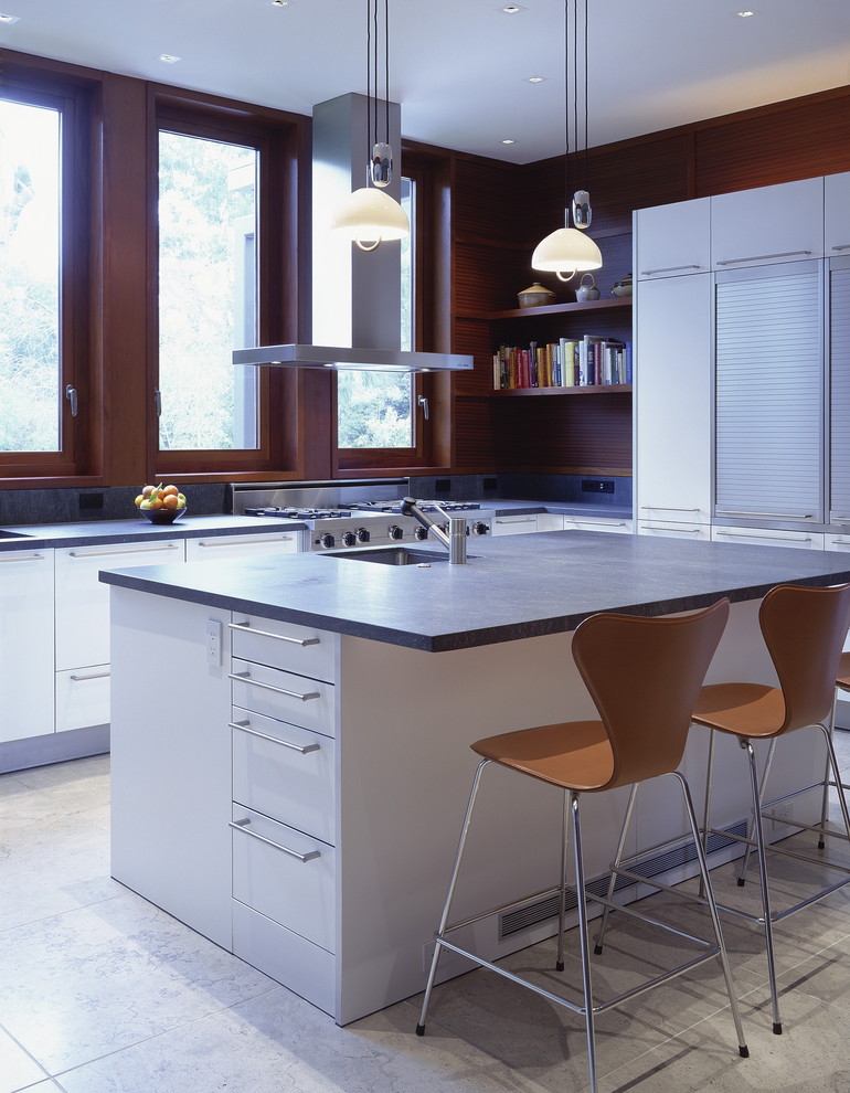 Modelo de cocina moderna con fregadero bajoencimera, armarios con paneles lisos, puertas de armario blancas y electrodomésticos de acero inoxidable