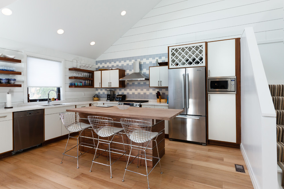 Kleine Klassische Wohnküche mit Doppelwaschbecken, Küchenrückwand in Blau, Küchengeräten aus Edelstahl, hellem Holzboden und Kücheninsel
