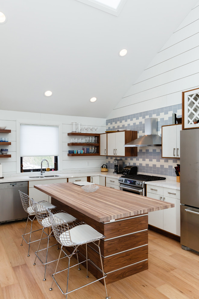Kleine Klassische Wohnküche mit Doppelwaschbecken, Küchenrückwand in Blau, Küchengeräten aus Edelstahl, hellem Holzboden und Kücheninsel