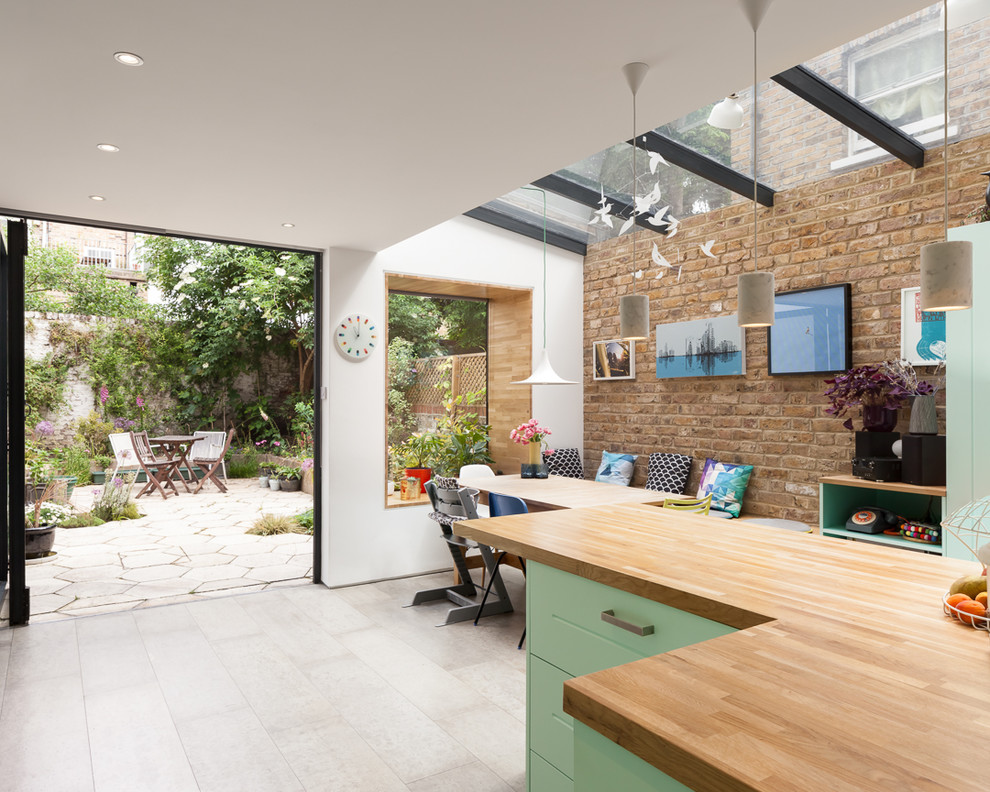 ロンドンにあるコンテンポラリースタイルのおしゃれなダイニングキッチン (エプロンフロントシンク、シェーカースタイル扉のキャビネット、緑のキャビネット、木材カウンター、グレーのキッチンパネル、セメントタイルのキッチンパネル、コンクリートの床、グレーの床) の写真