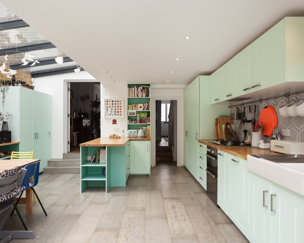 Bild på ett funkis kök och matrum, med en rustik diskho, skåp i shakerstil, gröna skåp, träbänkskiva, grått stänkskydd, stänkskydd i cementkakel, betonggolv och grått golv