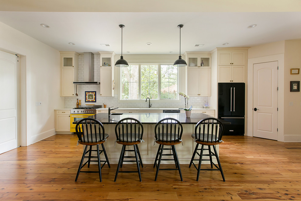 Inspiration for a mid-sized timeless single-wall medium tone wood floor eat-in kitchen remodel in Charleston with an undermount sink, shaker cabinets, white cabinets, white backsplash, subway tile backsplash, colored appliances and an island