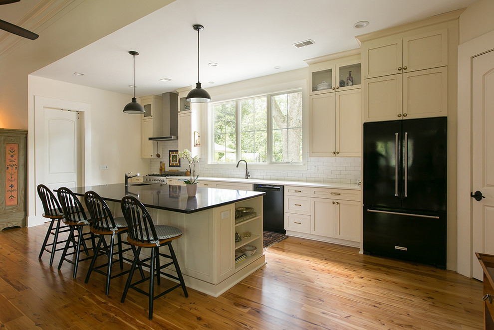 Example of a mid-sized classic single-wall medium tone wood floor eat-in kitchen design in Charleston with an undermount sink, shaker cabinets, white cabinets, white backsplash, subway tile backsplash, colored appliances and an island
