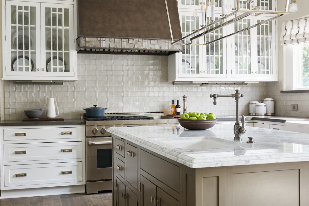 Transitional kitchen photo in Los Angeles with an undermount sink, glass-front cabinets, white cabinets, beige backsplash, stainless steel appliances and an island