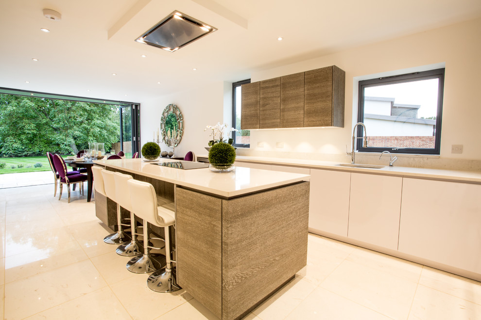 Moderne Wohnküche mit Unterbauwaschbecken, flächenbündigen Schrankfronten, hellbraunen Holzschränken, Kücheninsel, beigem Boden und weißer Arbeitsplatte in Oxfordshire