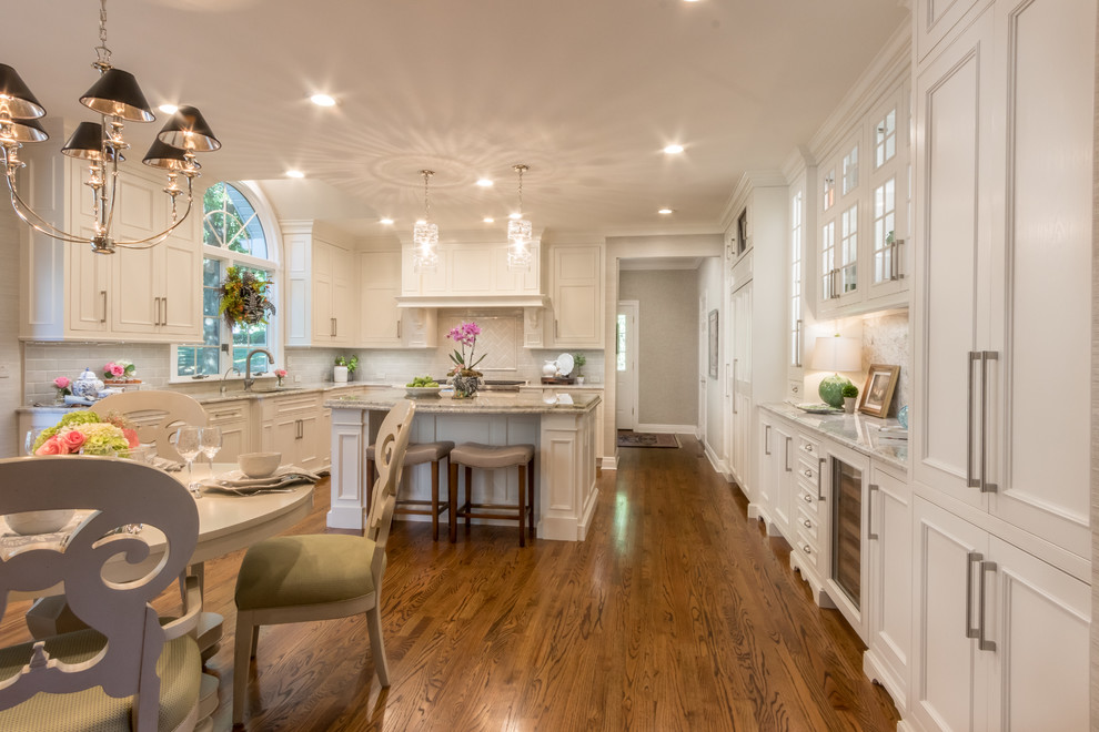 Inspiration for a large timeless u-shaped medium tone wood floor and brown floor eat-in kitchen remodel in St Louis with an undermount sink, recessed-panel cabinets, white cabinets, granite countertops, beige backsplash, ceramic backsplash, stainless steel appliances and an island