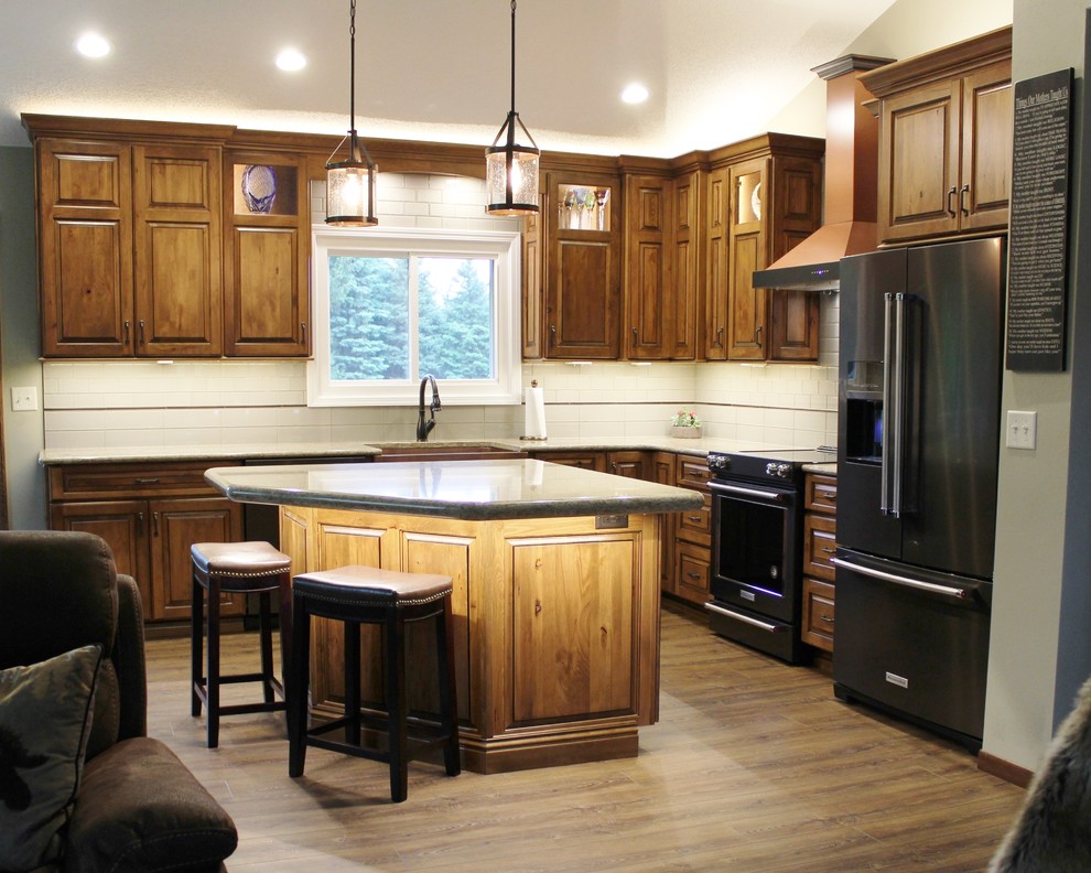 Rustik inredning av ett stort beige beige kök, med en rustik diskho, luckor med upphöjd panel, skåp i mellenmörkt trä, bänkskiva i kvarts, beige stänkskydd, stänkskydd i glaskakel, svarta vitvaror, vinylgolv, en köksö och brunt golv
