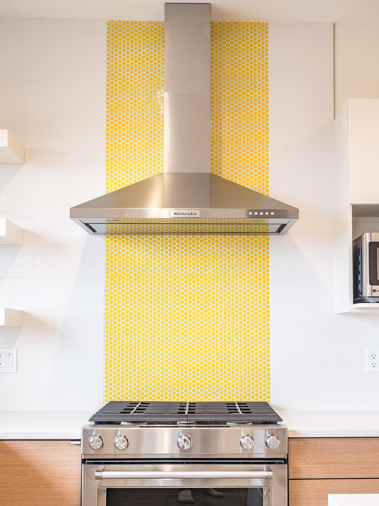 Bild på ett mellanstort nordiskt kök, med en dubbel diskho, släta luckor, skåp i mellenmörkt trä, bänkskiva i kvartsit, gult stänkskydd, stänkskydd i porslinskakel, rostfria vitvaror, vinylgolv, en köksö och grått golv