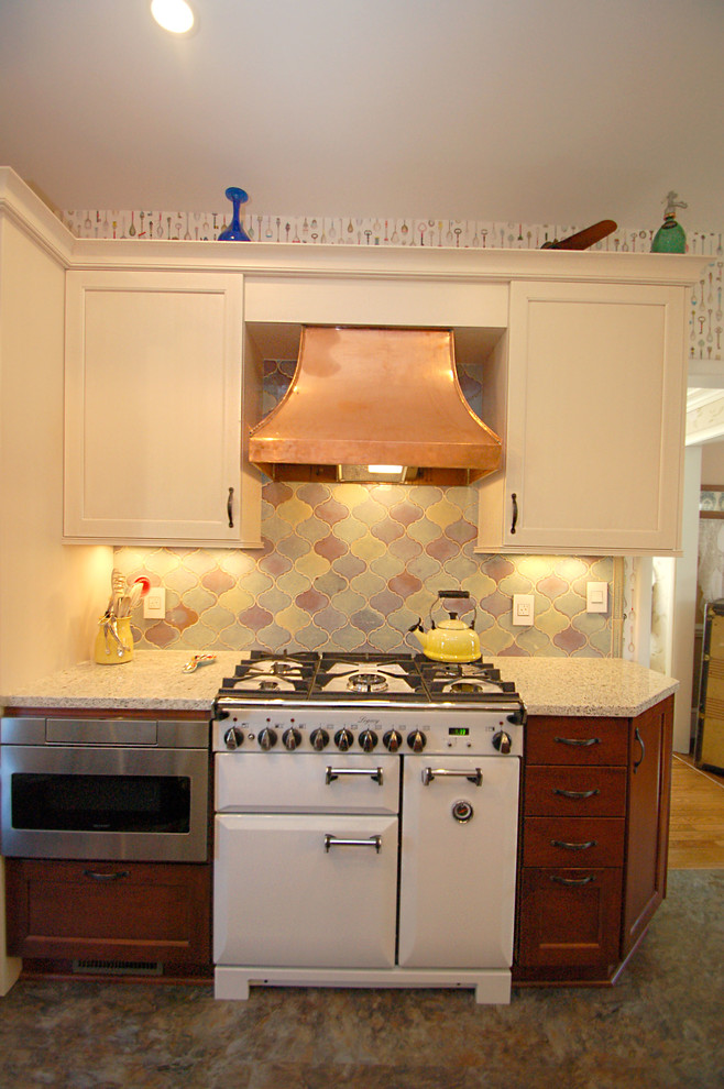 This is an example of a medium sized traditional l-shaped kitchen/diner in Newark with a submerged sink, recessed-panel cabinets, medium wood cabinets, engineered stone countertops, multi-coloured splashback, mosaic tiled splashback, stainless steel appliances, vinyl flooring and no island.