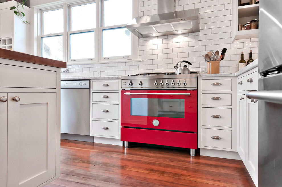 Enclosed kitchen - mid-sized country u-shaped carpeted and brown floor enclosed kitchen idea in Seattle with a farmhouse sink, shaker cabinets, white cabinets, wood countertops, white backsplash, subway tile backsplash, stainless steel appliances, an island and brown countertops