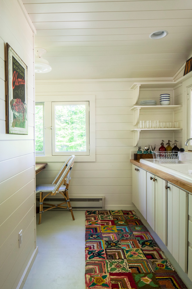 Foto de cocina lineal de estilo de casa de campo pequeña cerrada sin isla con fregadero encastrado, puertas de armario blancas, encimera de madera, suelo de cemento y armarios con paneles lisos