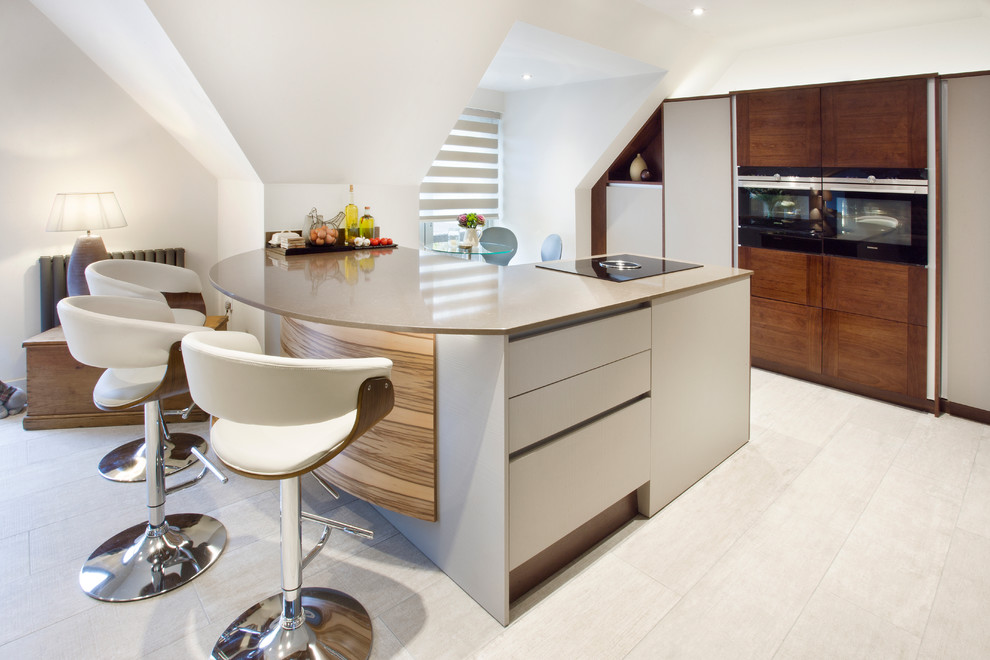 Photo of a large contemporary u-shaped open plan kitchen in West Midlands with flat-panel cabinets, dark wood cabinets, quartz worktops, a breakfast bar, grey floors, black appliances and brown worktops.