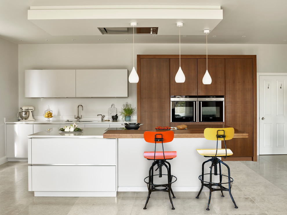 Einzeilige, Mittelgroße Moderne Wohnküche mit Doppelwaschbecken, weißen Schränken, Mineralwerkstoff-Arbeitsplatte, Elektrogeräten mit Frontblende, Kücheninsel, flächenbündigen Schrankfronten und Keramikboden in Surrey