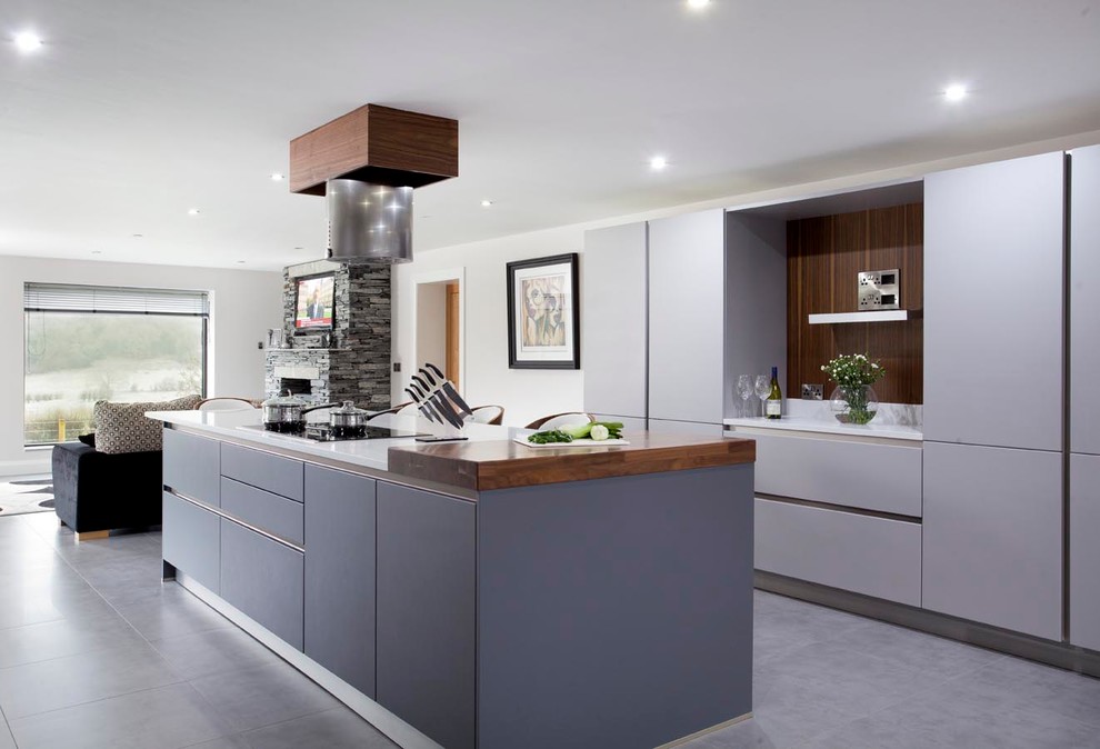 Inspiration for a medium sized contemporary galley open plan kitchen in Other with a submerged sink, flat-panel cabinets, grey cabinets, quartz worktops, white splashback, glass sheet splashback, stainless steel appliances, porcelain flooring and an island.