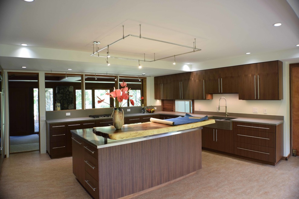 Photo of a large contemporary l-shaped kitchen in Hawaii with a belfast sink, flat-panel cabinets, dark wood cabinets, engineered stone countertops, stainless steel appliances and an island.