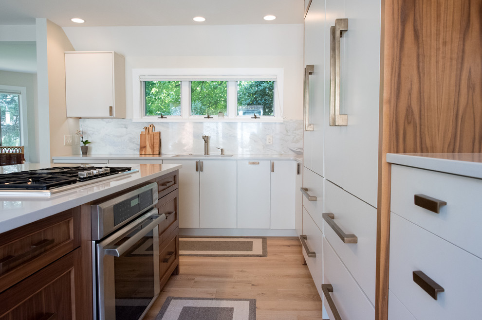 Mid-sized trendy l-shaped light wood floor and beige floor open concept kitchen photo in Philadelphia with an undermount sink, flat-panel cabinets, white cabinets, quartz countertops, white backsplash, stone slab backsplash, paneled appliances and an island