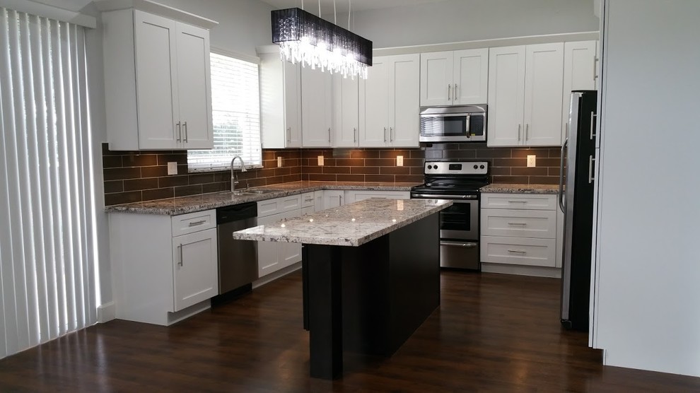 This is an example of a medium sized contemporary l-shaped kitchen/diner in Miami with a double-bowl sink, shaker cabinets, white cabinets, granite worktops, brown splashback, metro tiled splashback, stainless steel appliances, dark hardwood flooring, an island and brown floors.