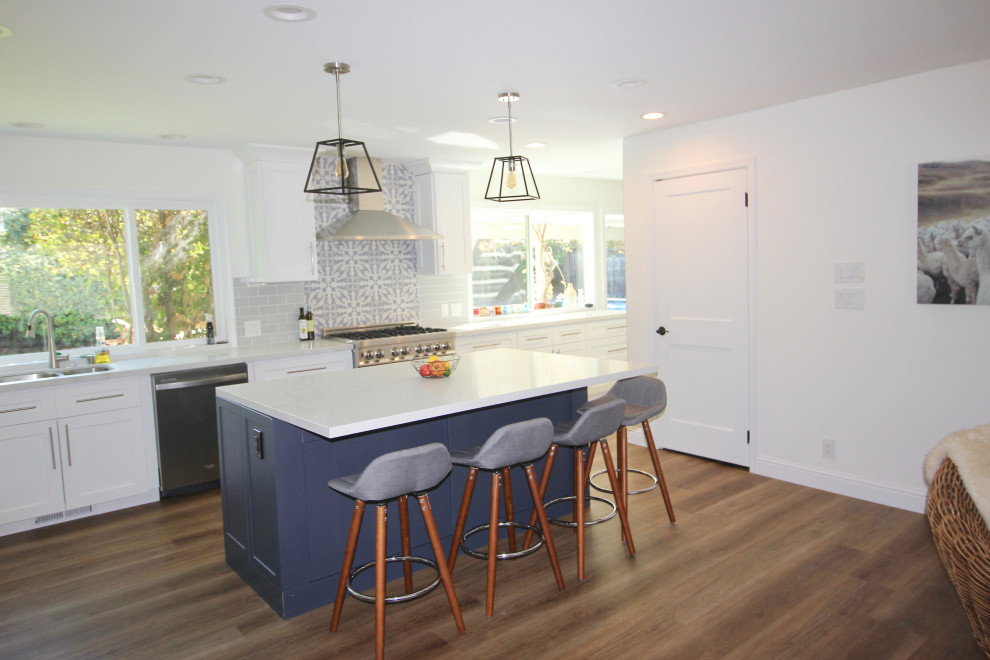 Large transitional l-shaped vinyl floor and brown floor open concept kitchen photo in San Francisco with an undermount sink, shaker cabinets, white cabinets, quartz countertops, blue backsplash, ceramic backsplash, stainless steel appliances, an island and gray countertops