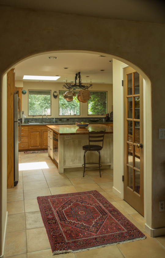 Large mediterranean enclosed kitchen in San Francisco with a submerged sink, raised-panel cabinets, medium wood cabinets, ceramic splashback, stainless steel appliances, ceramic flooring, an island and beige floors.