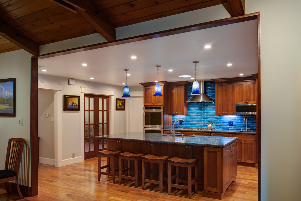 Photo of a medium sized traditional single-wall kitchen/diner in San Francisco with a submerged sink, shaker cabinets, medium wood cabinets, granite worktops, blue splashback, metro tiled splashback, stainless steel appliances, medium hardwood flooring and an island.