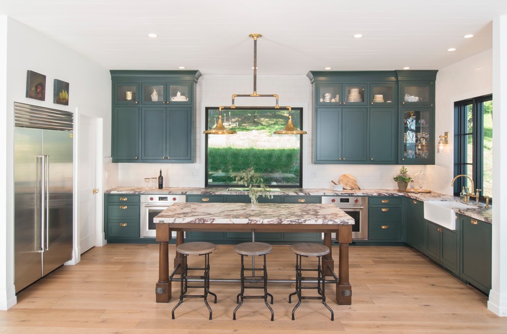 Inspiration for a large cottage galley medium tone wood floor and brown floor eat-in kitchen remodel in San Francisco with a drop-in sink, flat-panel cabinets, green cabinets, marble countertops, white backsplash, ceramic backsplash, stainless steel appliances, an island and white countertops