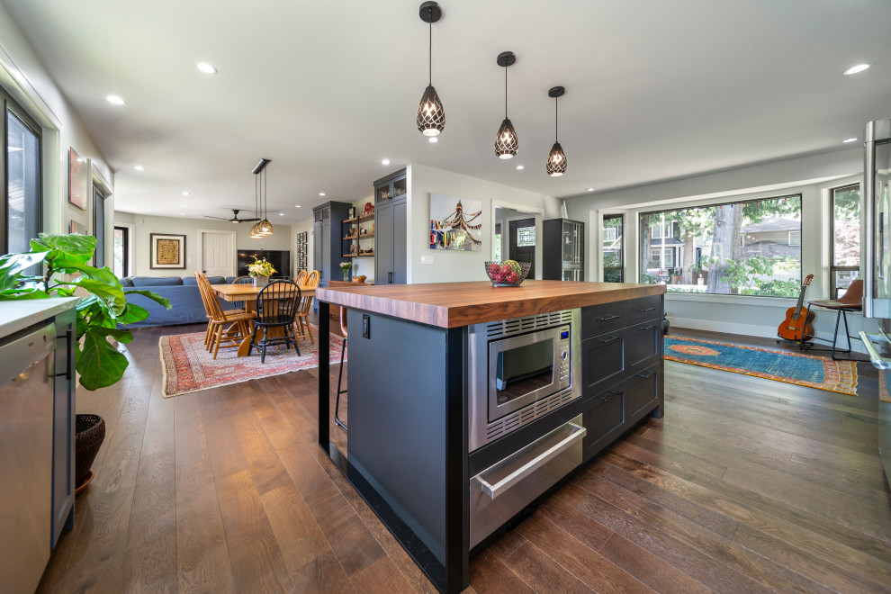 Mid-sized trendy l-shaped dark wood floor and brown floor eat-in kitchen photo in Vancouver with an undermount sink, shaker cabinets, blue cabinets, wood countertops, beige backsplash, terra-cotta backsplash, stainless steel appliances, an island and brown countertops