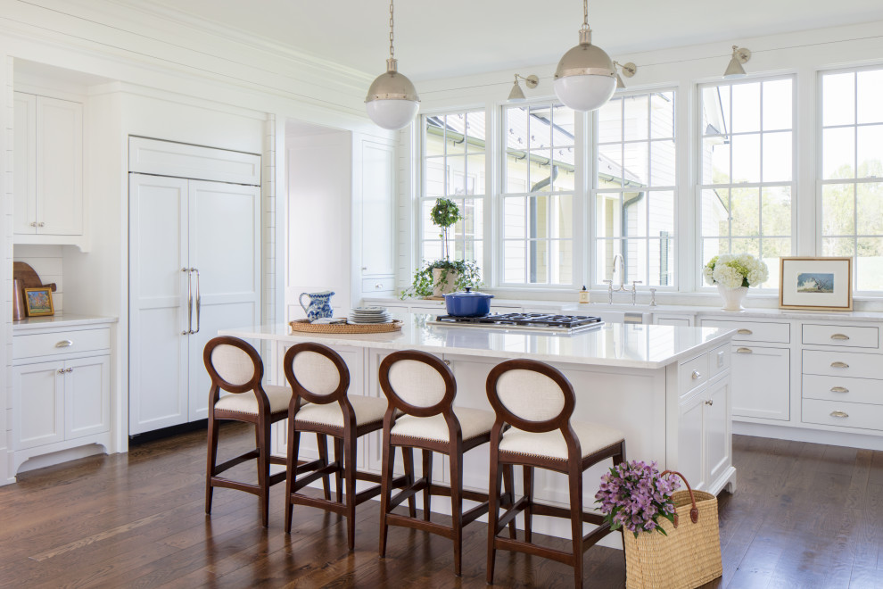 Eat-in kitchen - mid-sized coastal l-shaped medium tone wood floor and brown floor eat-in kitchen idea in Richmond with a farmhouse sink, beaded inset cabinets, white cabinets, quartzite countertops, white backsplash, wood backsplash, paneled appliances, an island and white countertops