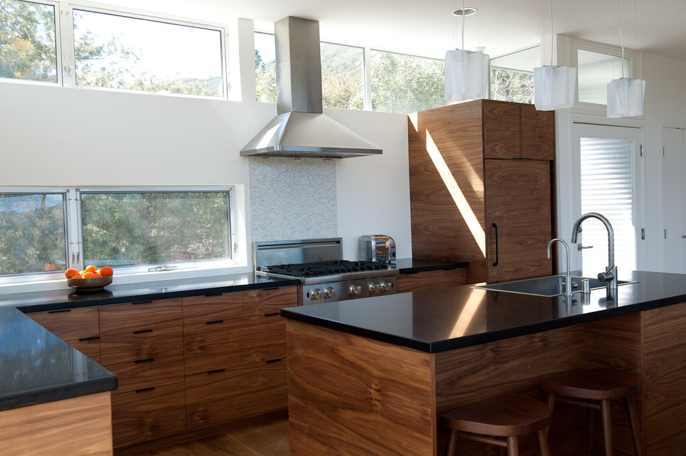 Immagine di una cucina a L design con elettrodomestici da incasso, lavello sottopiano, ante in stile shaker, ante in legno bruno e top in superficie solida