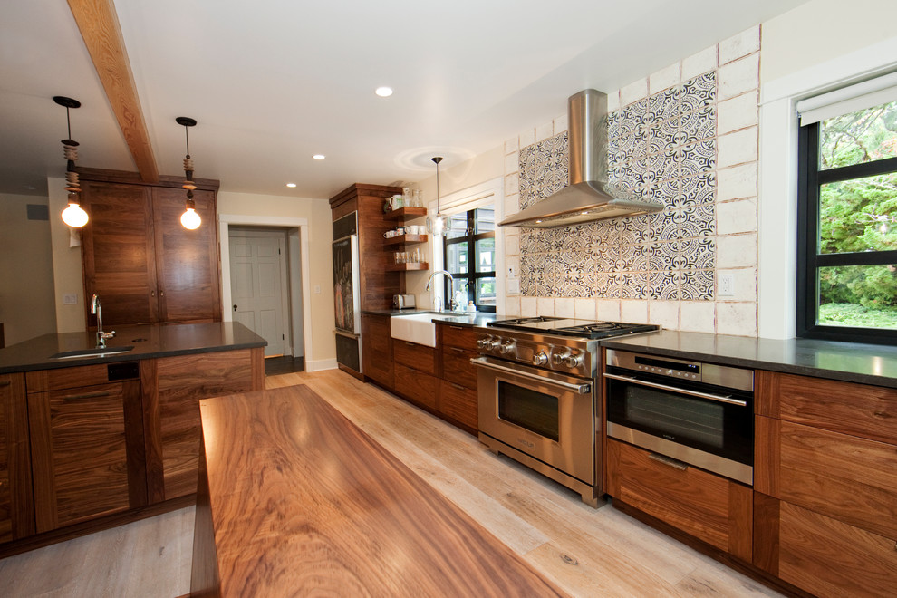 Immagine di una grande cucina contemporanea con lavello stile country, ante in legno bruno, top in granito, elettrodomestici in acciaio inossidabile e parquet chiaro