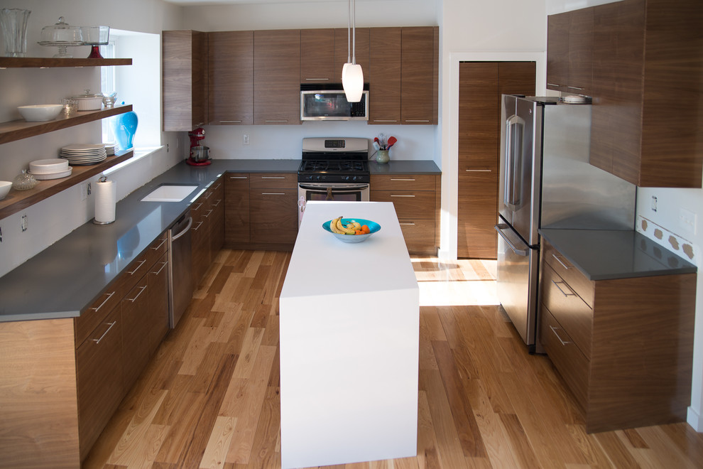 Foto di una cucina minimal di medie dimensioni con lavello sottopiano, ante lisce, ante in legno bruno, top in quarzo composito, elettrodomestici in acciaio inossidabile e parquet chiaro