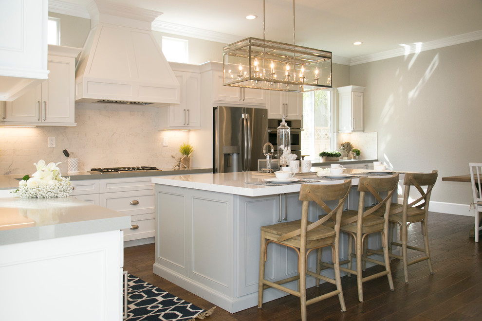 Inspiration for a large transitional l-shaped medium tone wood floor eat-in kitchen remodel in San Diego with shaker cabinets, white cabinets, solid surface countertops, white backsplash, mosaic tile backsplash, stainless steel appliances and an island