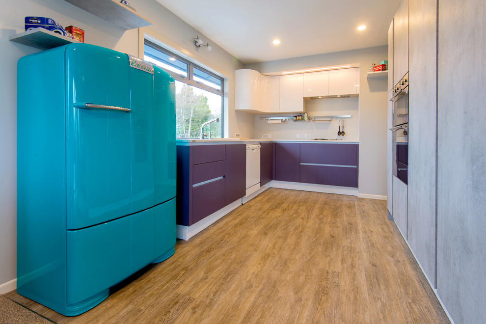 На фото: п-образная кухня среднего размера в стиле ретро с двойной мойкой, плоскими фасадами, фиолетовыми фасадами, столешницей из ламината, полом из винила и кладовкой без острова