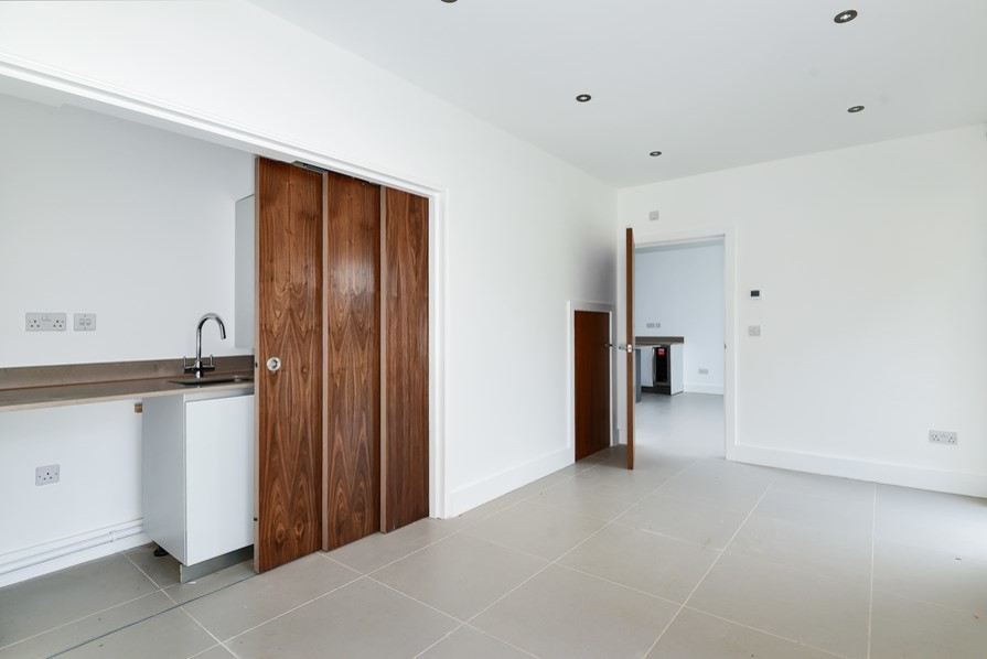 Mittelgroße Moderne Küche in L-Form mit flächenbündigen Schrankfronten, weißen Schränken, Quarzit-Arbeitsplatte, Kücheninsel und beiger Arbeitsplatte in Hertfordshire